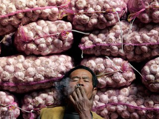 Chinese Garlic Lord relaxes, thinking of all the money he is making with his stash of garlic. Another good reason to Buy Local.