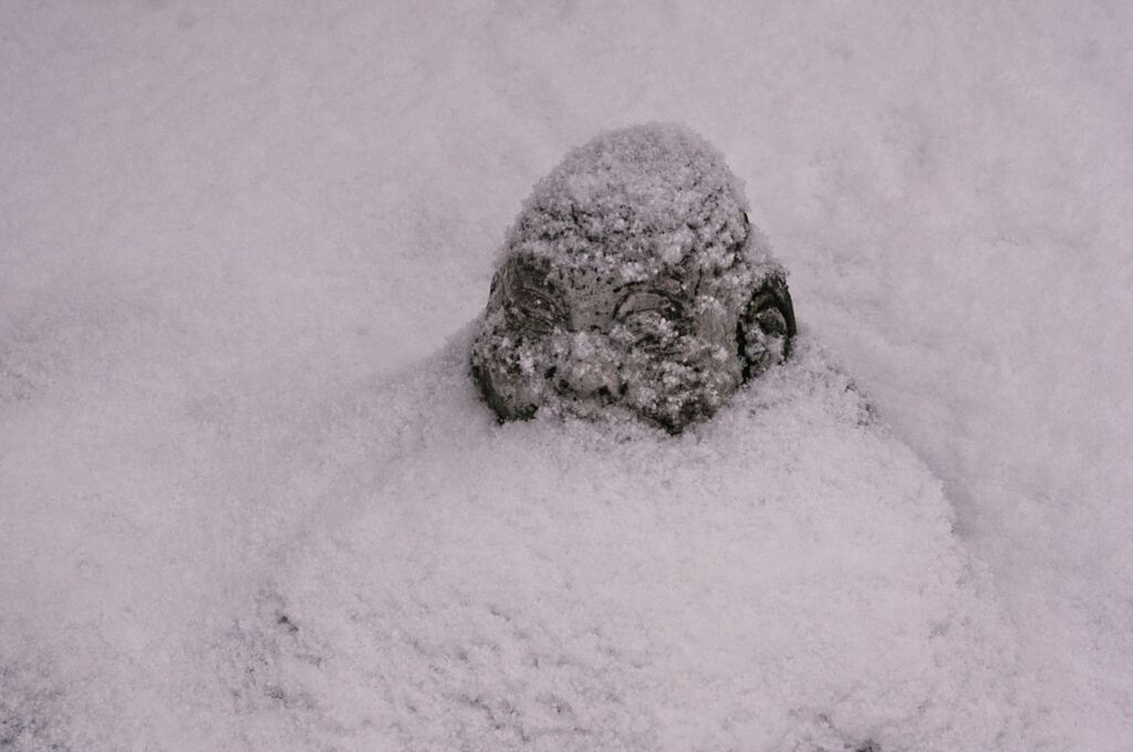 Cold garden Buddha statue under snow
